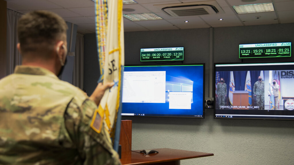 Col. Joel Lindeman, commander, Defense Information Systems Agency(DISA) Europe, presents the unit guidon to DISA Director, Vice Adm. Nancy Norton, during a virtual change of command ceremony held simultaneously at Patch Barracks, Stuttgart-Vaihingen, Germany, and DISA headquarters, Fort Meade, Md. Due to the global COVID-19 pandemic, military changes of commands have adopted social distancing measures or shifted to the virtual landscape to minimize the risk of transmission of the virus. (U.S. Army photo by Kenneth G. Takada)