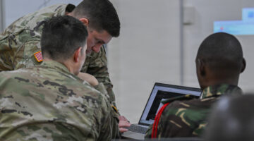 U.S. Army Chief Warrant Officer 2 Scott Lowry, senior host analyst, and Chief Warrant Officer 2 Benjamin Brown, cyber operations technician, with the 200th Cyber Protection Team, U.S. Army Cyber Protection Brigade, assist a member of the Tanzania People’s Defence Force while attending a course on defensive cyber operations during exercise Justified Accord 26, Dar Es Salaam, Tanzania, March 5, 2026. (U.S Air Force photo by Staff Sgt. Jan K. Valle)