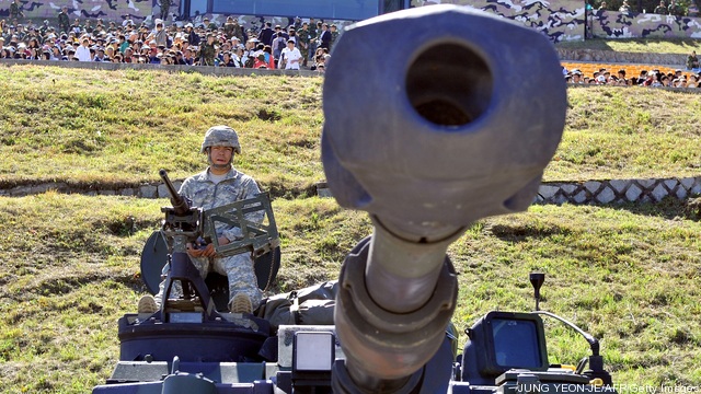 A US soldier sits on the top of M109A6 P