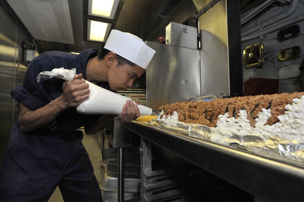 A Navy chef frosts a Thanksgiving cake on the USS Jason Dunham, a destroyer deployed to the Arabian Sea and named in memory of a Marine who died earning Medal of Honor.