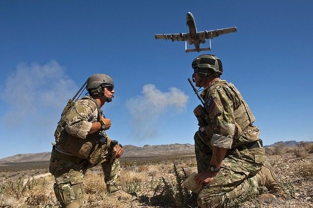 An A-10 "Warthog" flies low over two ground troops.