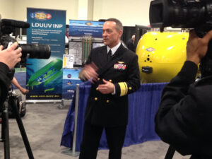 Rear Adm. Mathias Winter, head of the Office of Naval Research, shows off a robotic mini-sub, the Large Diameter Unmanned Underwater Vehicle (LDUUV).