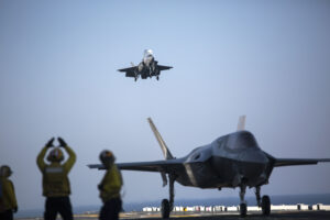 A sailor aboard the USS Wasp (LHD-1) signals to the pilot of an F-35B Lightning II Joint Strike Fighter to land as it arrives for the first phase of operational testing, May 18, 2015. The short take-off, vertical landing capabilities of the F-35B are crucial to the mission of the Marine Corps and necessary for operation aboard a Navy amphibious ship. The aircraft are stationed with Marine Fighter Attack Training Squadron 501, Marine Aircraft Group 31, 2nd Marine Aircraft Wing, Beaufort, South Carolina and Marine Fighter Attack Squadron 121, Marine Aircraft Group 13, 3rd Marine Aircraft Wing, Yuma, Arizona. (U.S. Marine Corps photo by Lance Cpl. Remington Hall/Released)