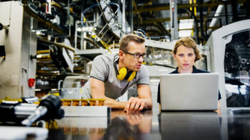 Engineers working on laptop in a large printer